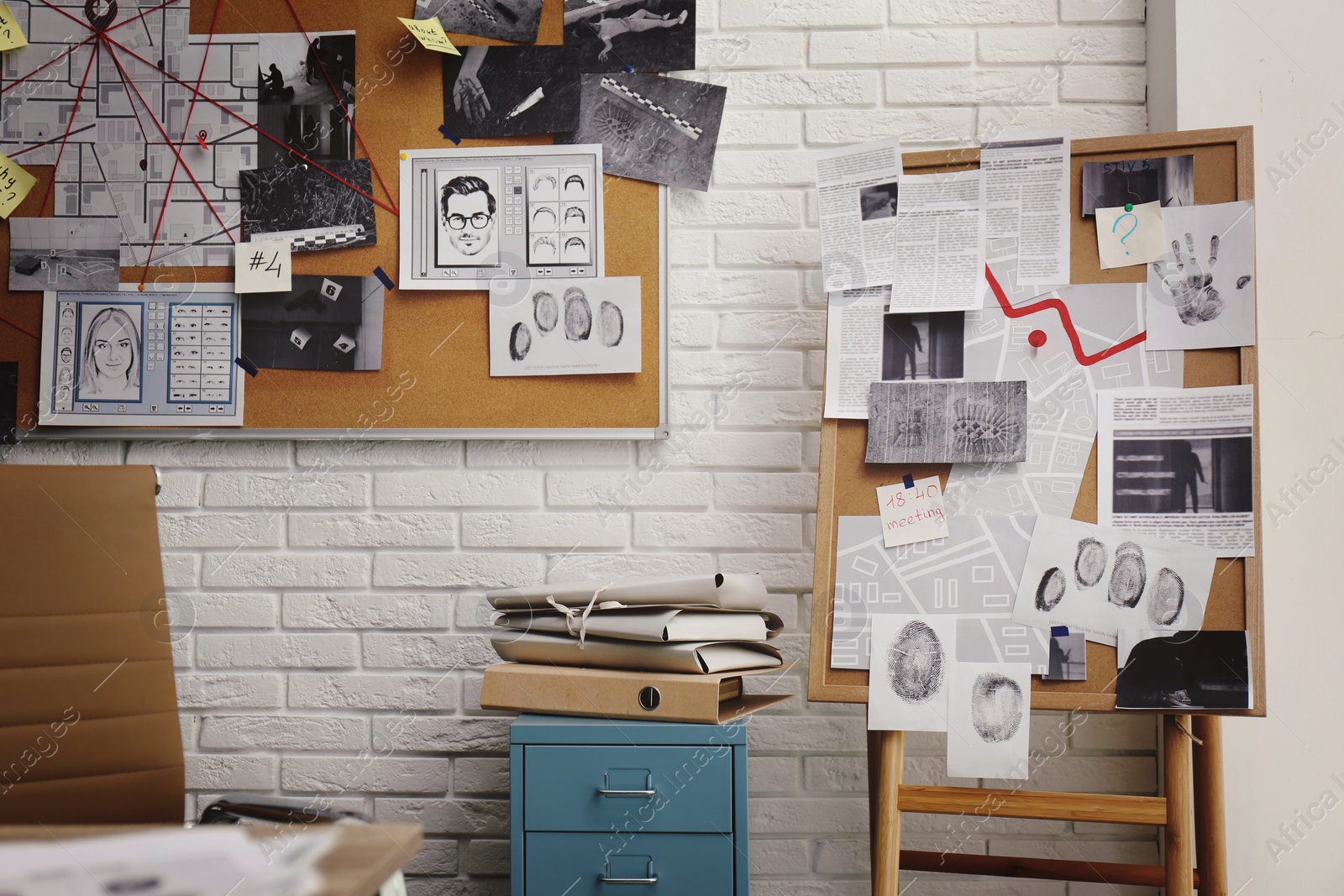 Photo of Boards with crime scene photos and maps near white brick wall in detective office