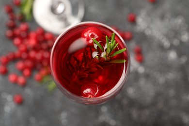 Photo of Tasty cranberry cocktail with rosemary in glass on gray table, top view