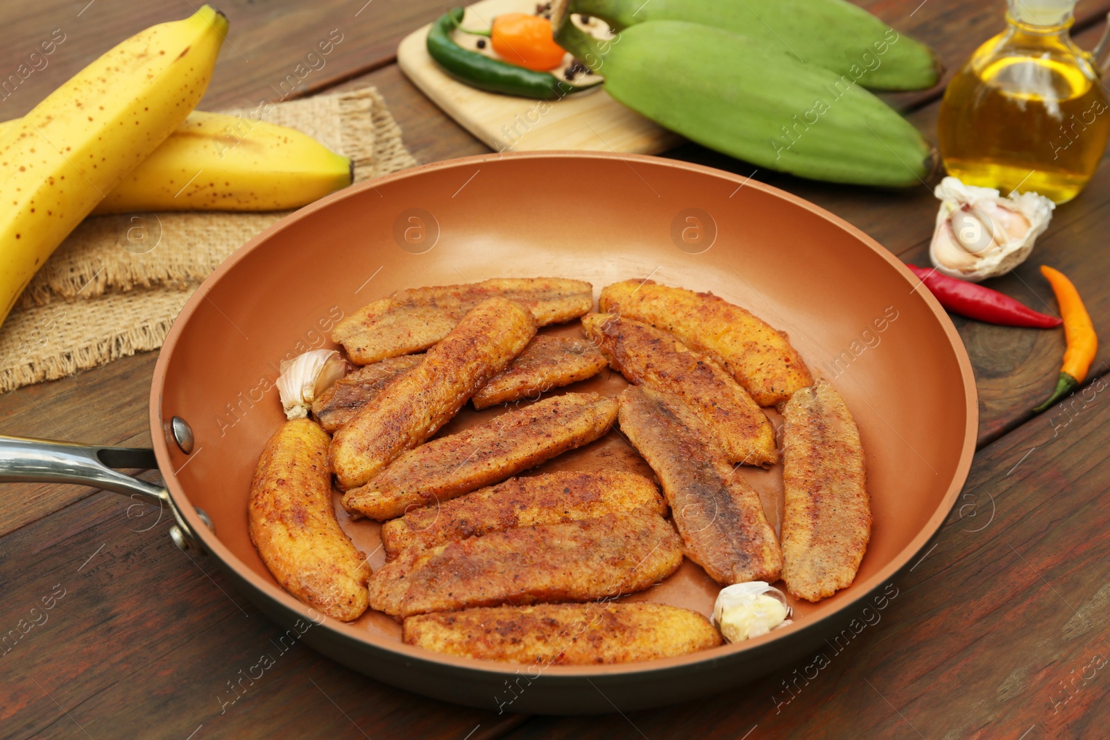 Photo of Delicious fried bananas, fresh fruits and different peppers on wooden table