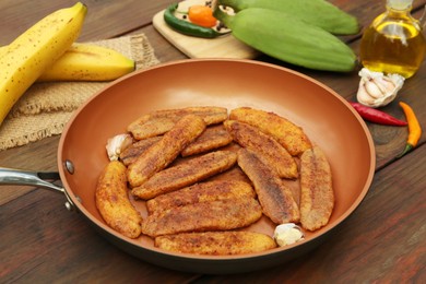 Delicious fried bananas, fresh fruits and different peppers on wooden table