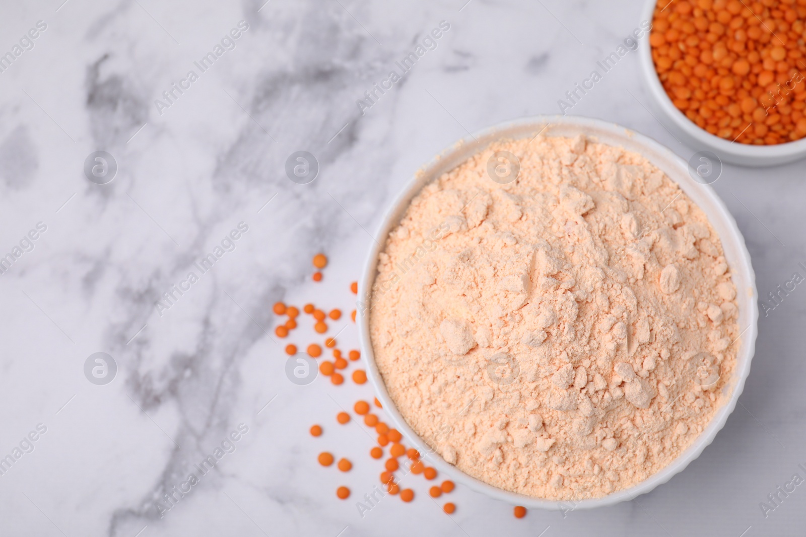 Photo of Lentil flour and seeds on white marble table, flat lay. Space for text