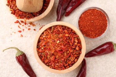 Photo of Chili pepper flakes and pods on light textured table, flat lay