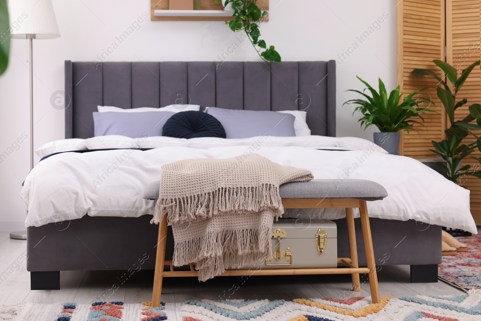 Photo of Stylish bedroom with double bed and beautiful green houseplants. Modern interior