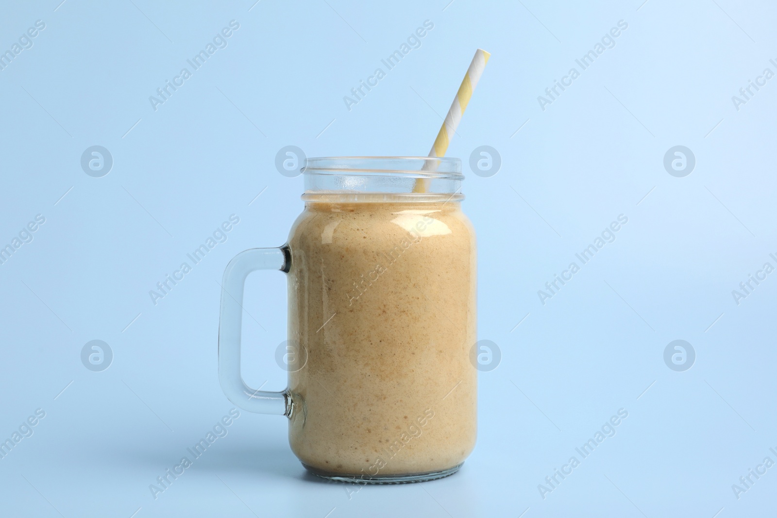 Photo of Mason jar with delicious fruit smoothie on light blue background