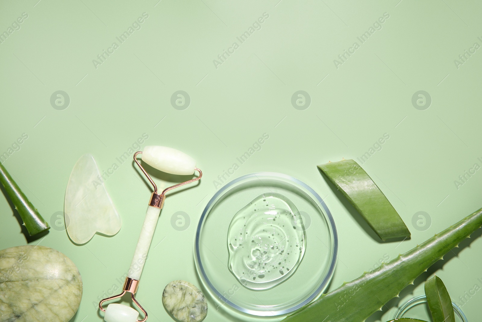 Photo of Flat lay composition with cosmetic product and cut aloe leaves on pale green background. Space for text