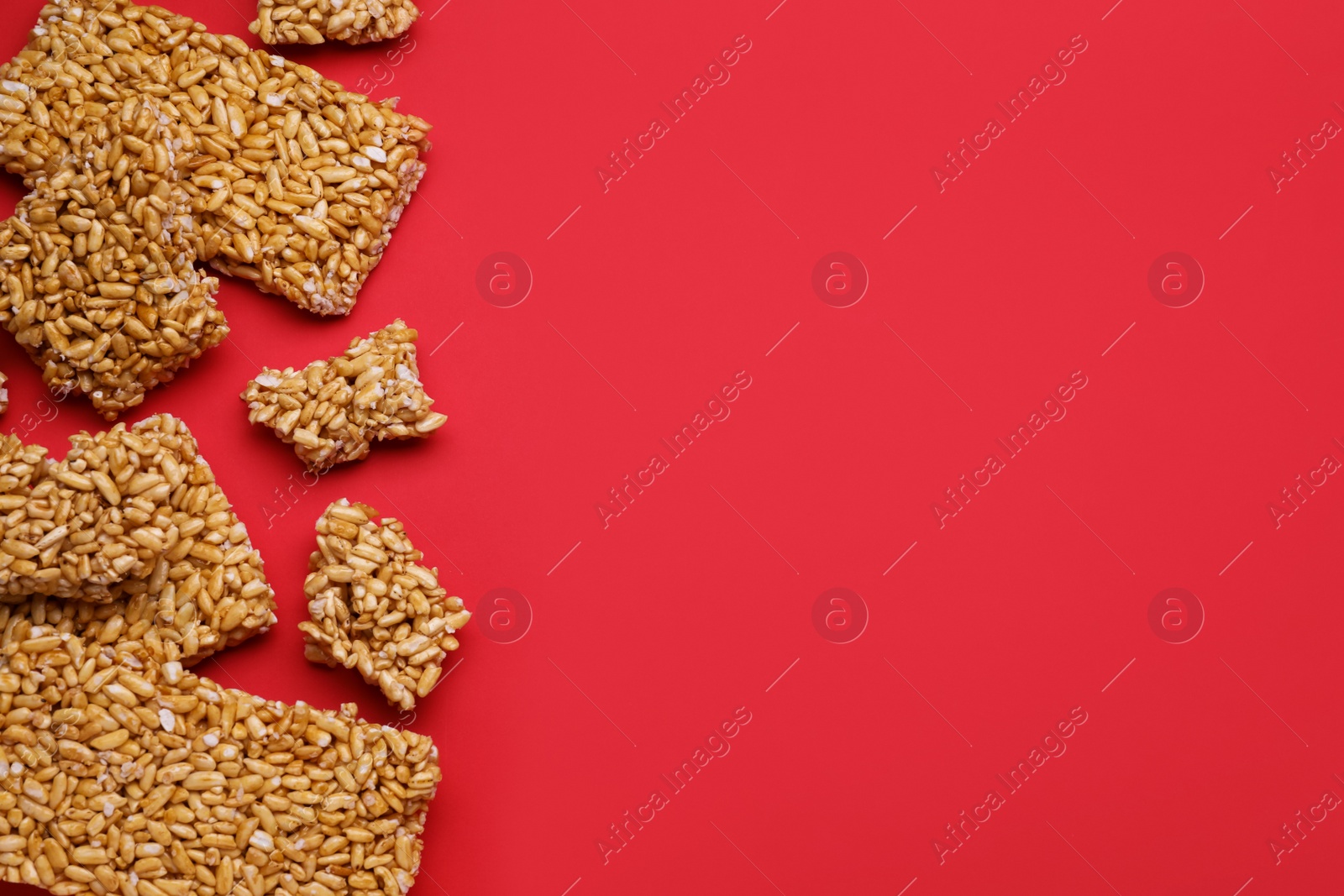 Photo of Puffed rice bars (kozinaki) on red background, flat lay. Space for text