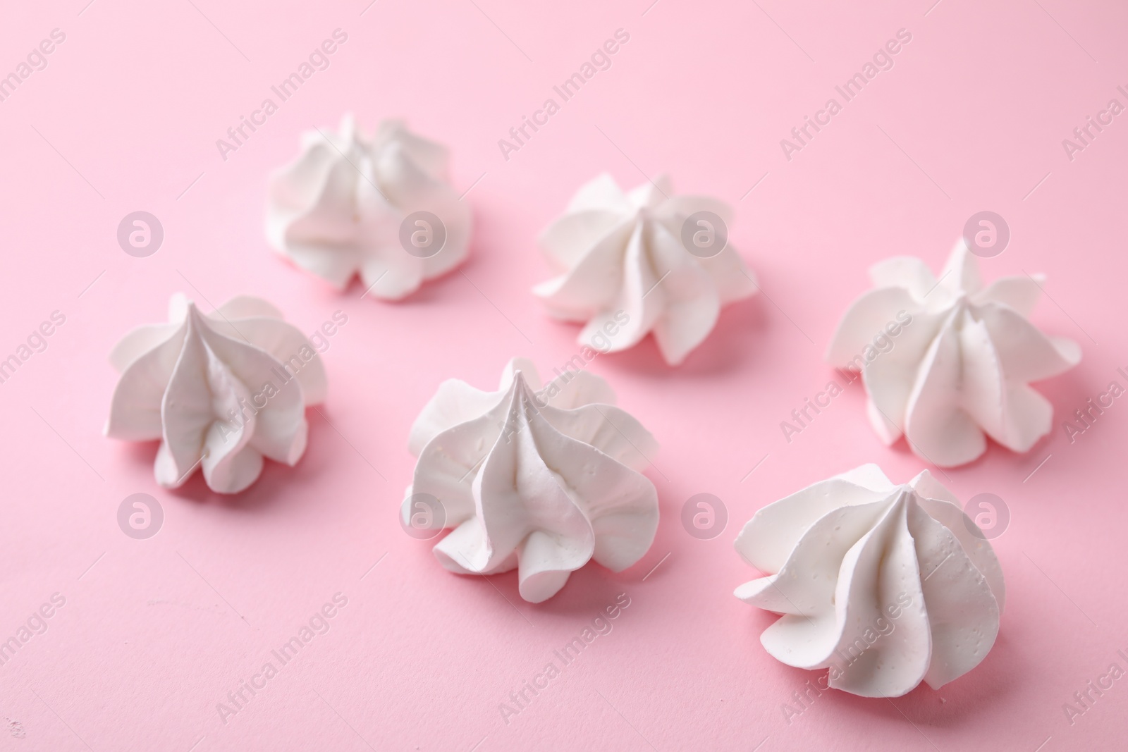 Photo of Many tasty meringue cookies on pink background