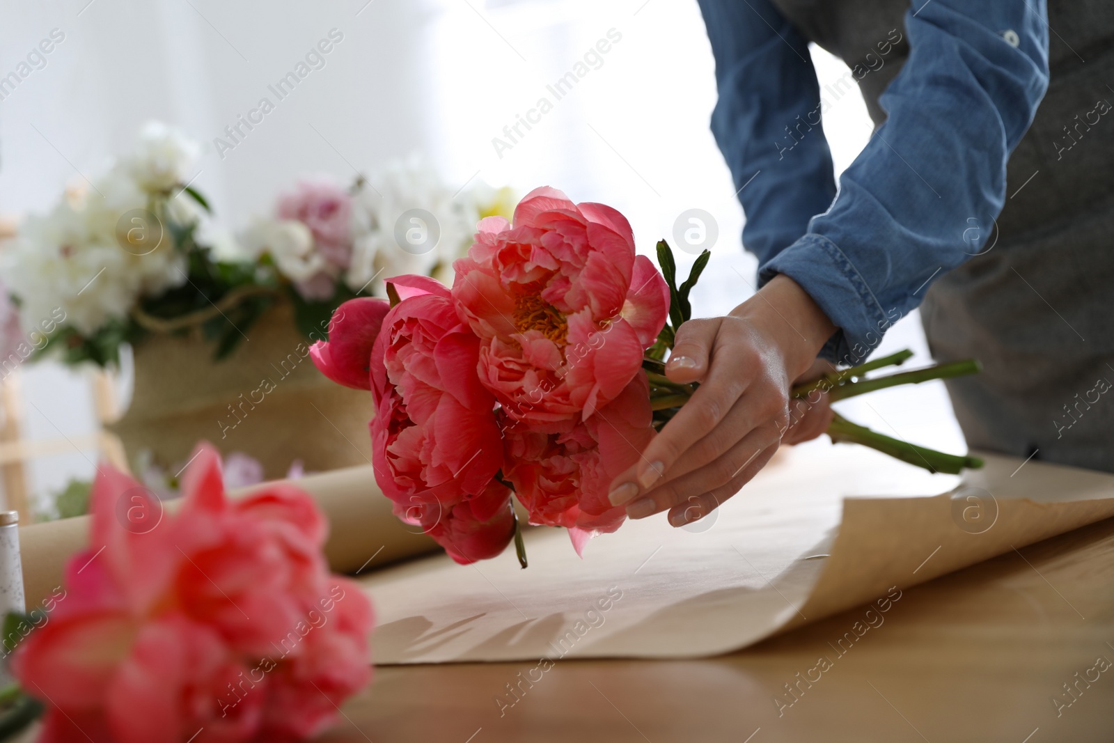 Photo of Florist making beautiful peony bouquet at table, closeup