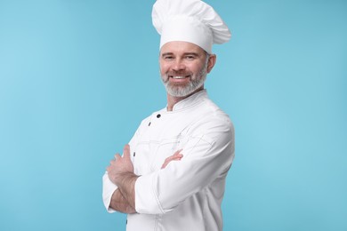 Happy chef in uniform on light blue background