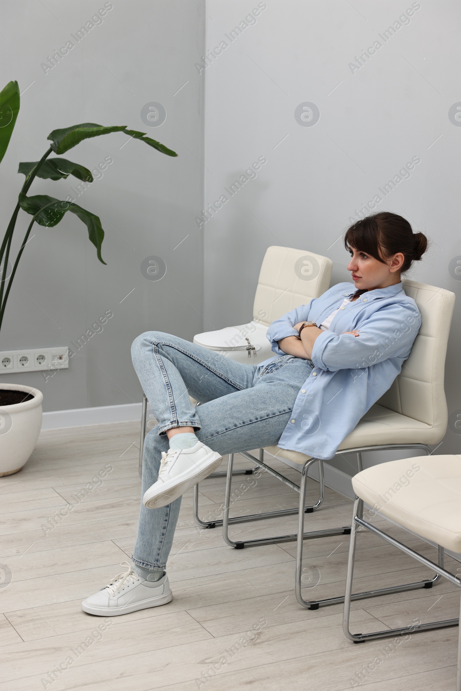 Photo of Woman sitting on chair and waiting for appointment indoors