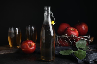 Photo of Composition with delicious apple cider on black table