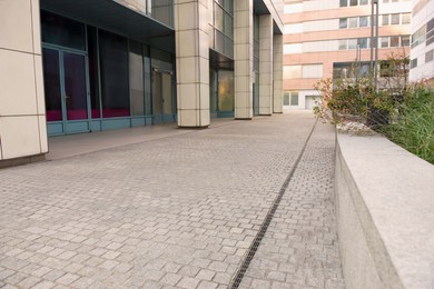 Photo of Tiled pavement near building outdoors. Sidewalk covering