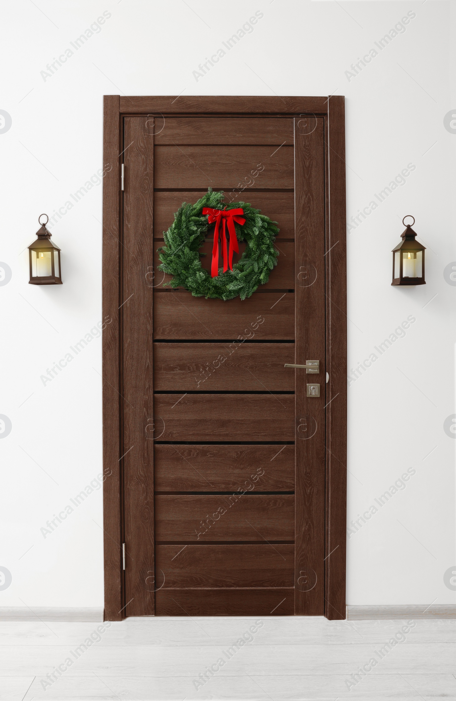 Photo of Beautiful Christmas wreath with red bow hanging on door