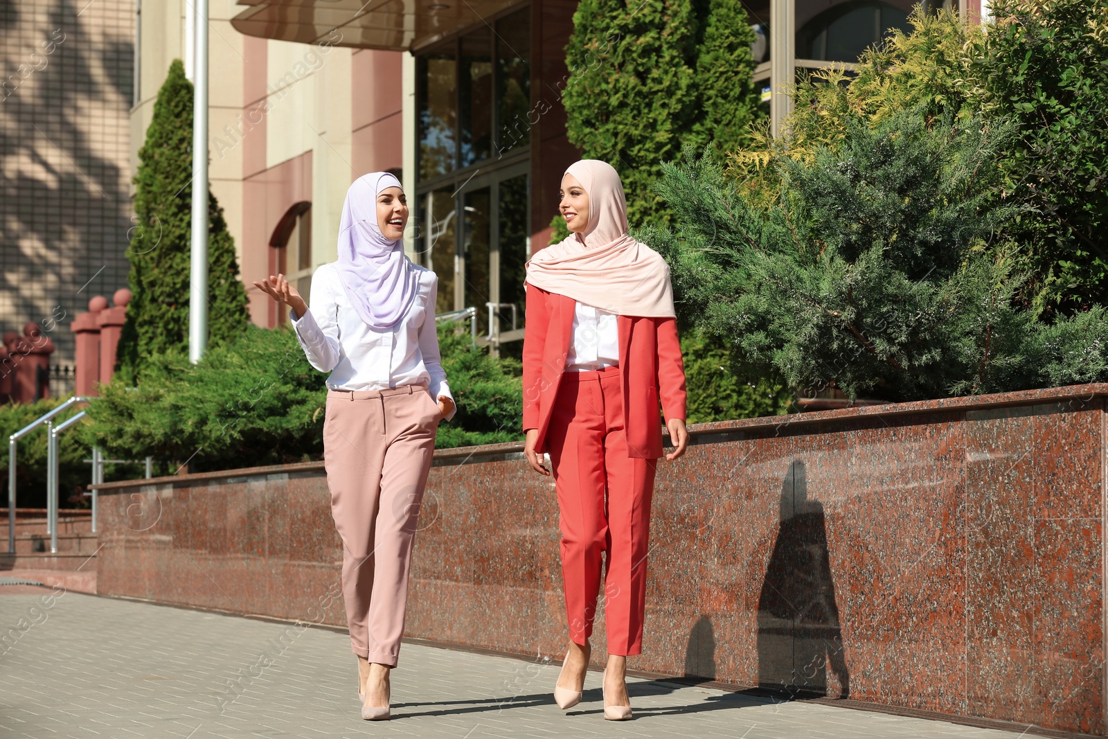 Photo of Muslim women in hijabs talking outdoors on sunny day