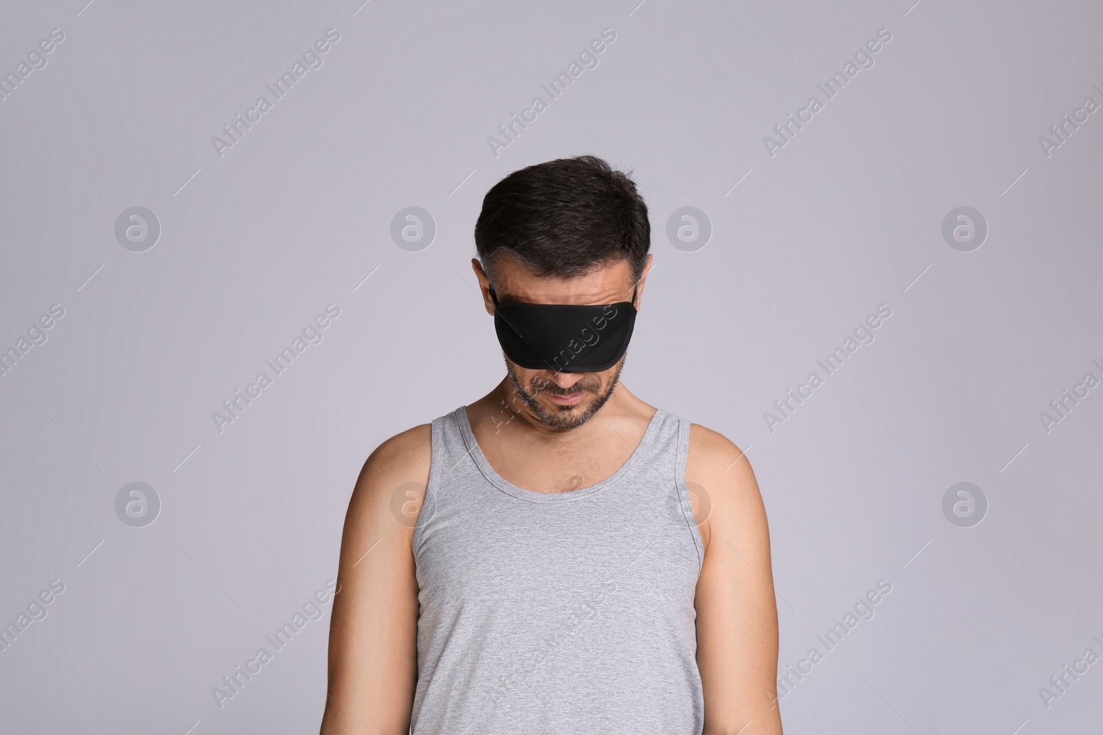 Photo of Man with eye mask in sleepwalking state on grey background