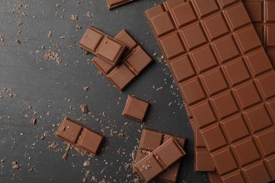 Pieces of tasty chocolate on grey table, flat lay