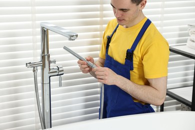 Young plumber repairing metal faucet in bathroom