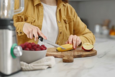 Photo of Woman preparing ingredients for tasty smoothie at white marble table in kitchen, closeup