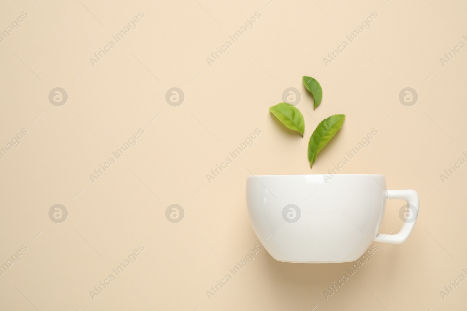 Photo of Fresh tea leaves and cup on beige background, top view. Space for text