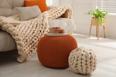 Tray with cup of tea and cookies on stylish comfortable pouf in room. Home design
