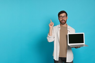 Handsome man with laptop on light blue background