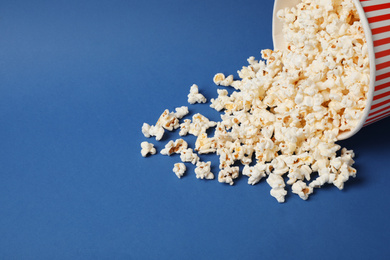 Photo of Delicious popcorn in paper bucket on blue background