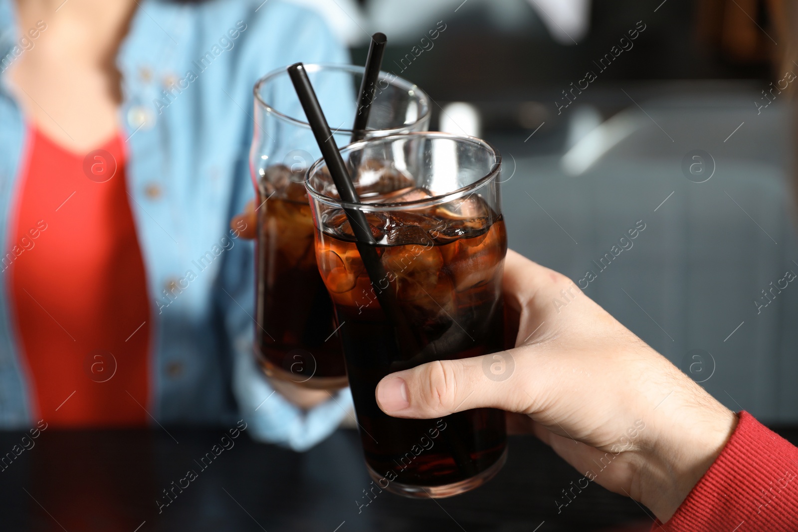 Photo of Young couple with glasses of cola at table indoors, closeup