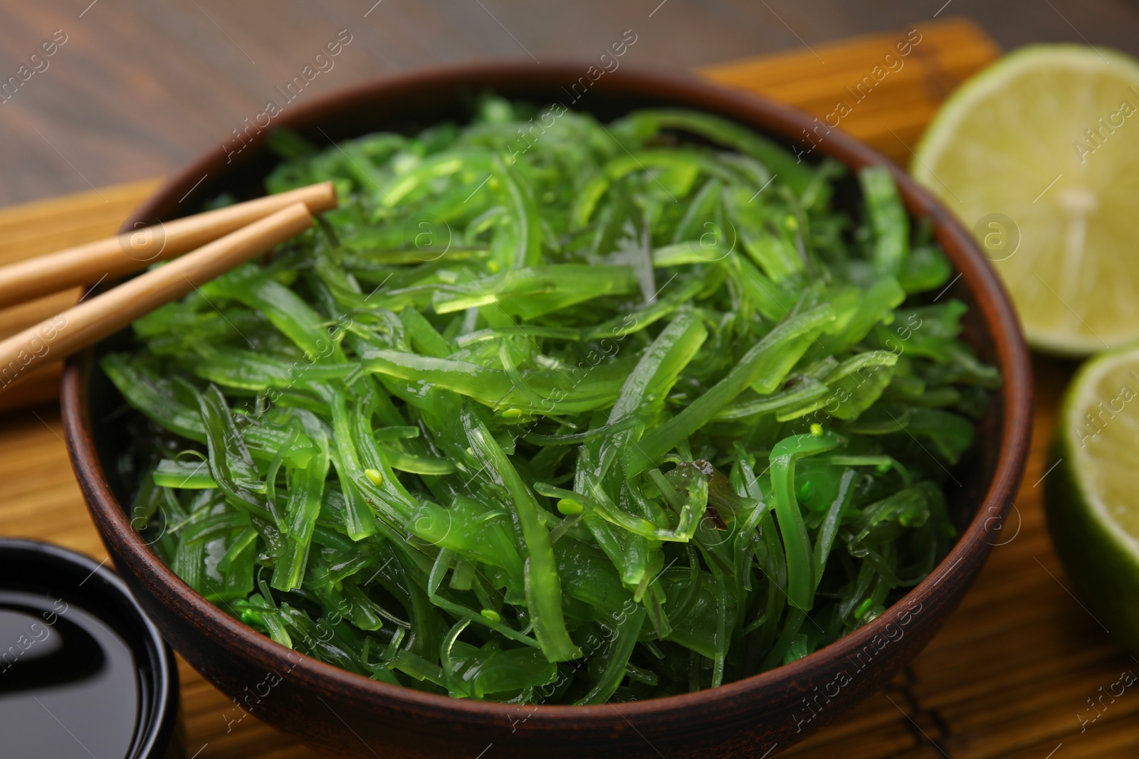 Photo of Tasty seaweed salad in bowl served on table, closeup