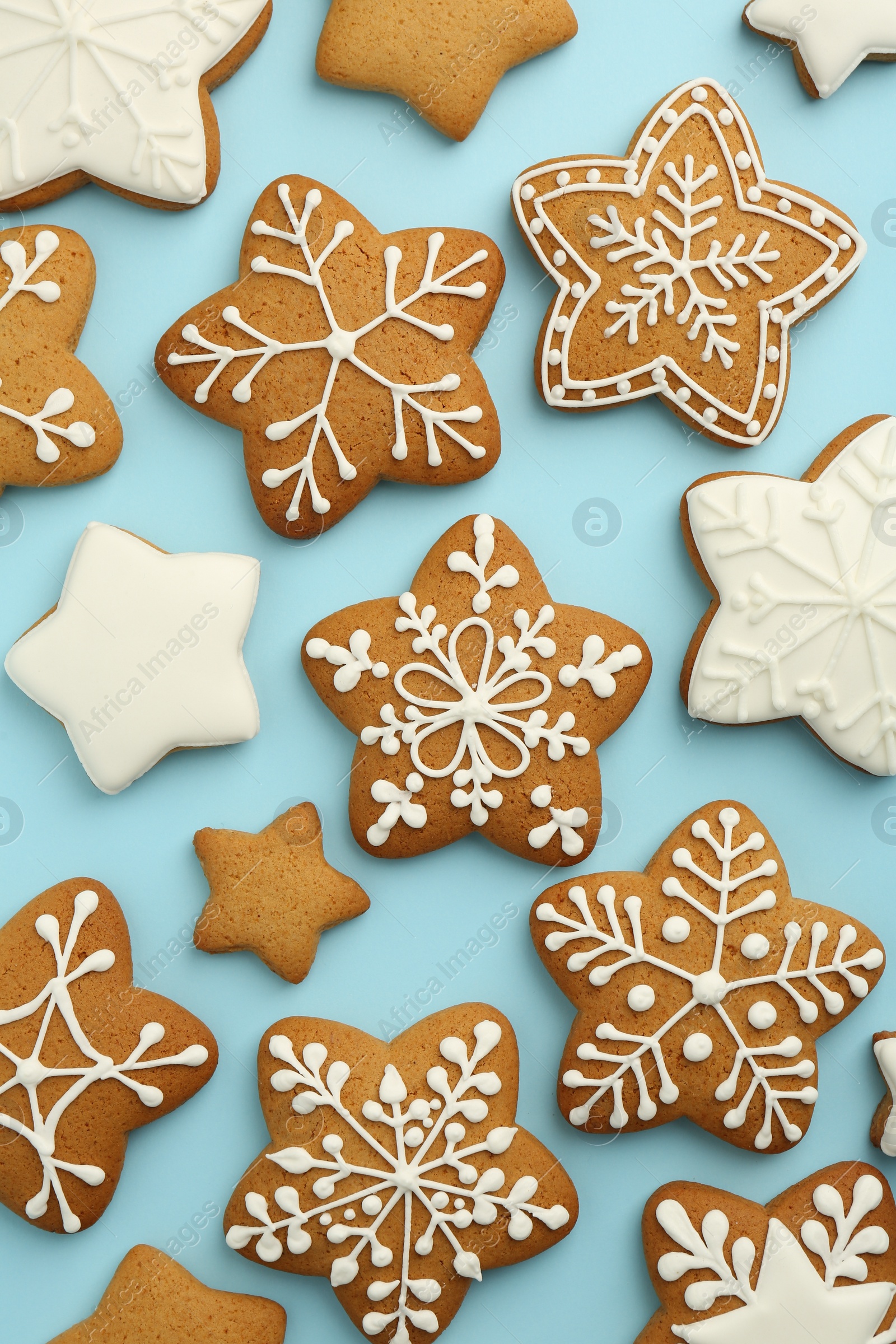 Photo of Tasty star shaped Christmas cookies with icing on light blue background, flat lay