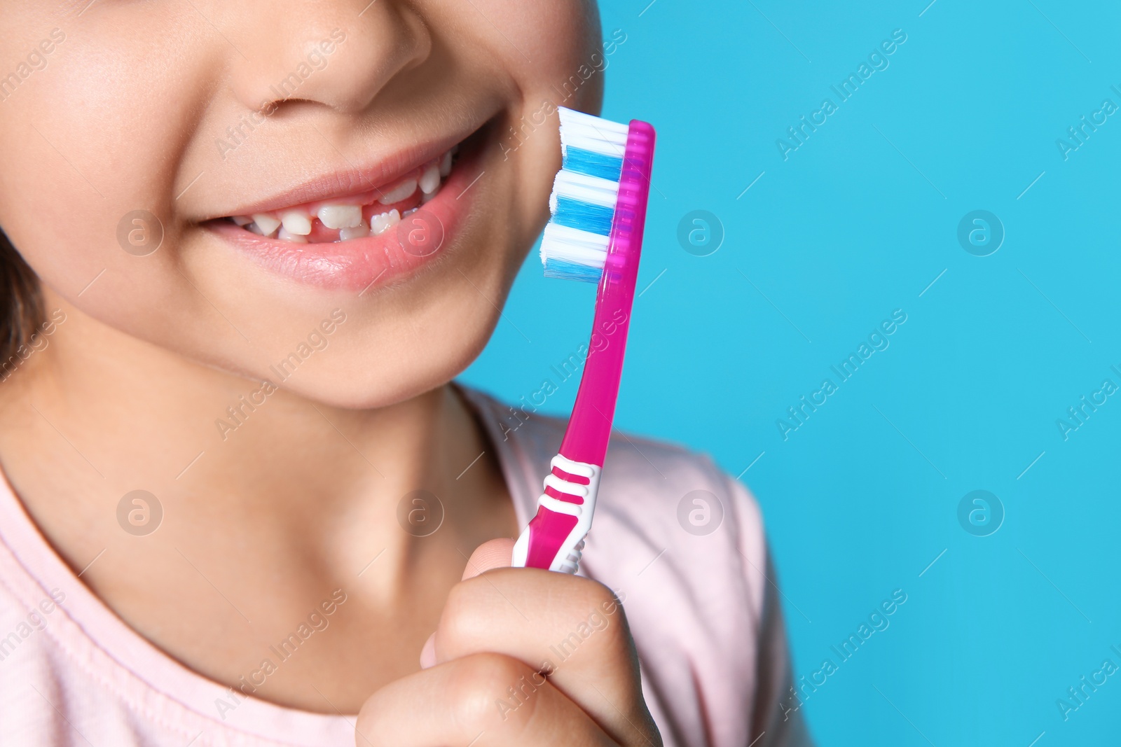 Photo of Little girl with toothbrush on color background, closeup. Space for text