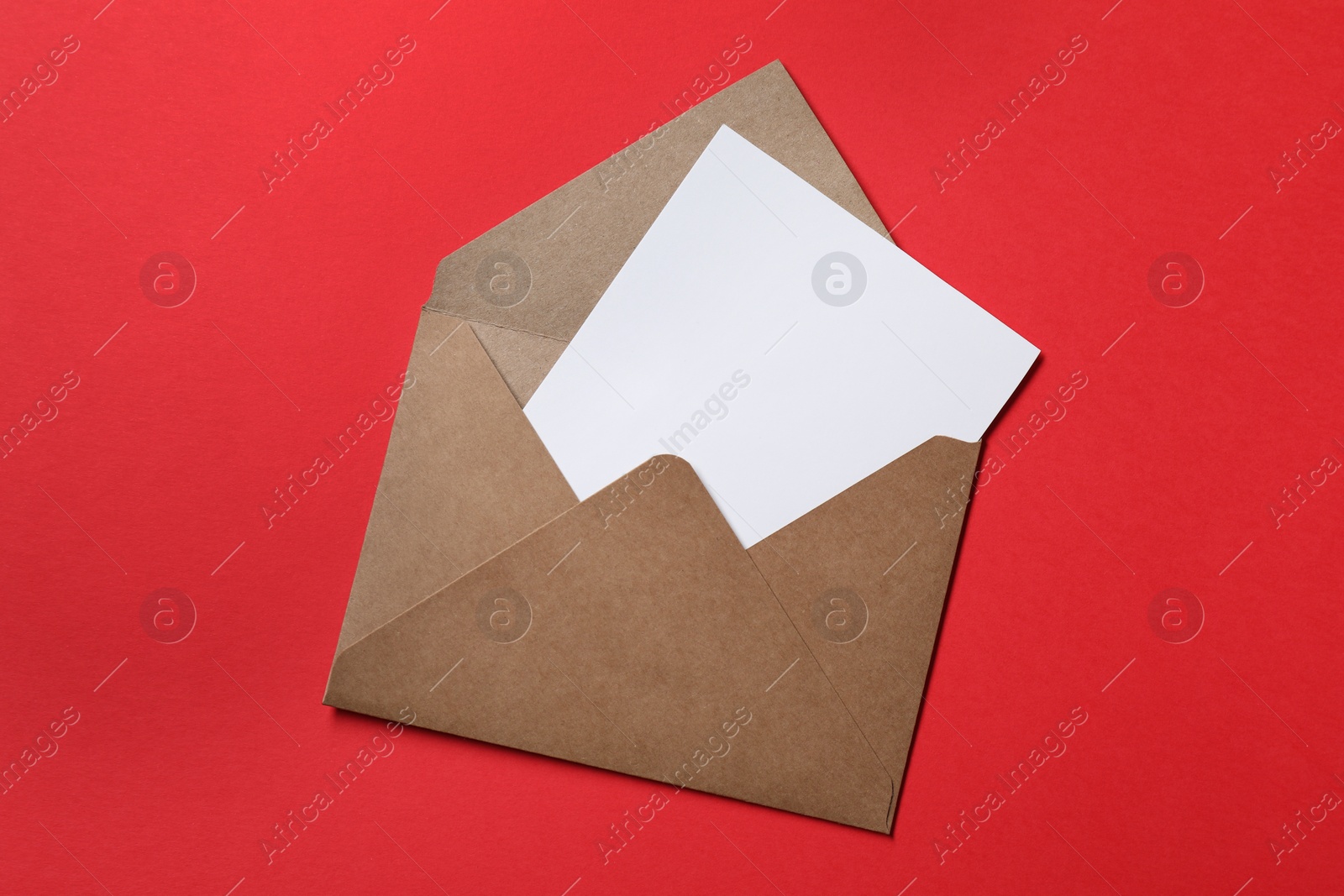 Photo of Letter envelope with card on red background, top view