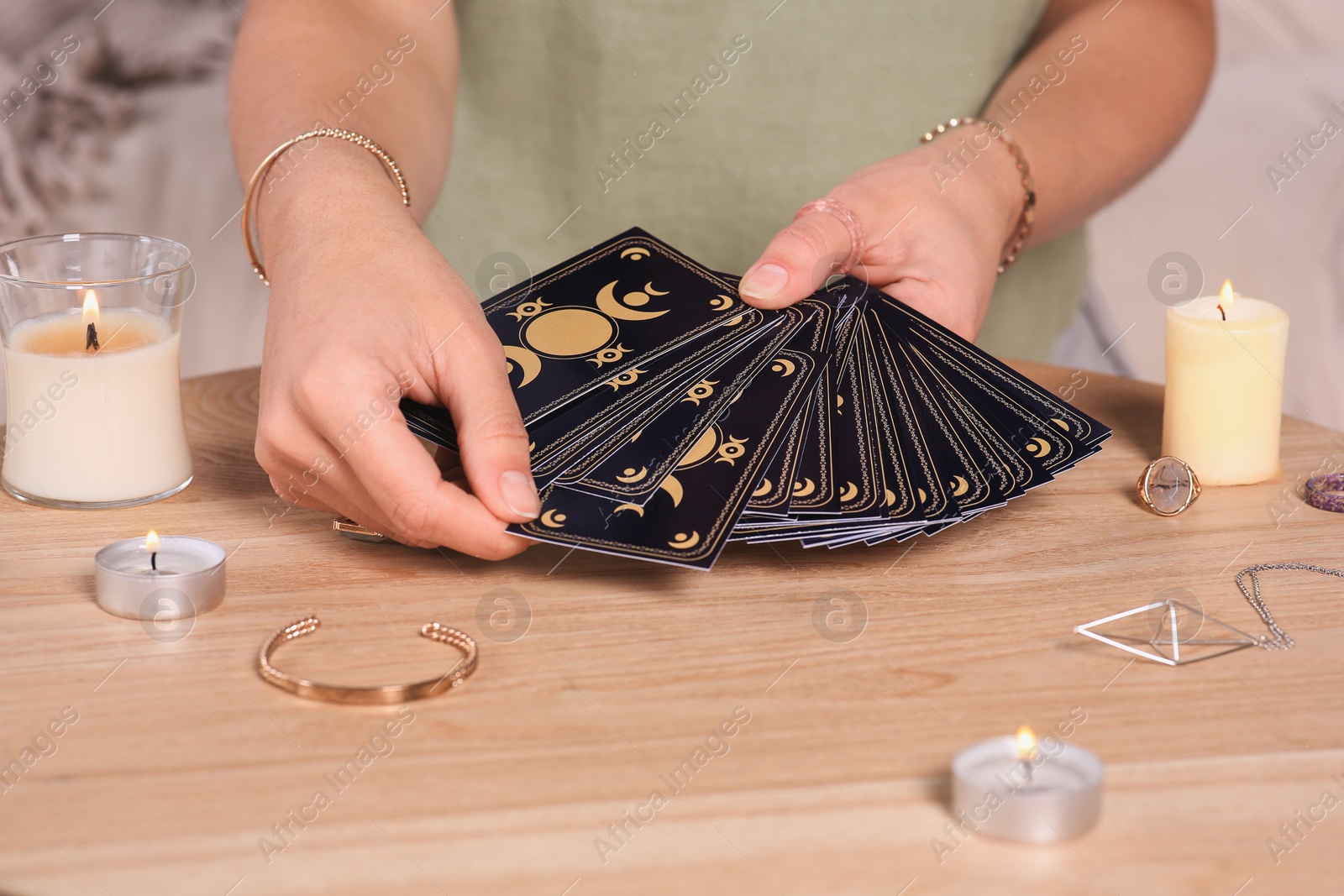 Photo of Soothsayer predicting future with tarot cards at table indoors, closeup