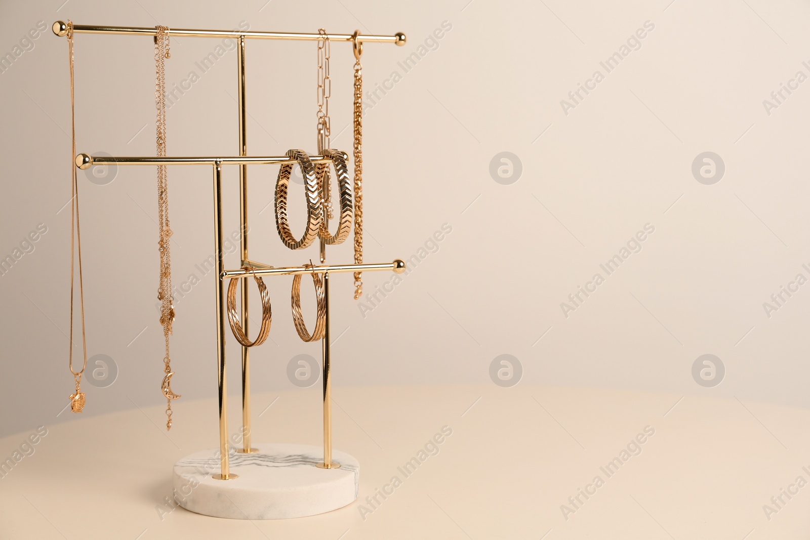 Photo of Holder with set of luxurious jewelry on white table. Space for text