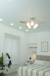 Photo of Ceiling fan, bed and houseplant in stylish bedroom