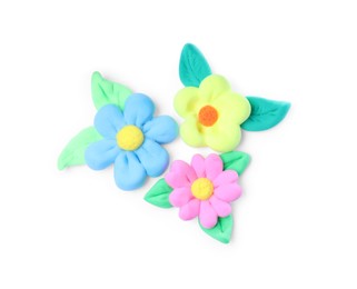 Colorful flowers with leaves made from play dough on white background, top view