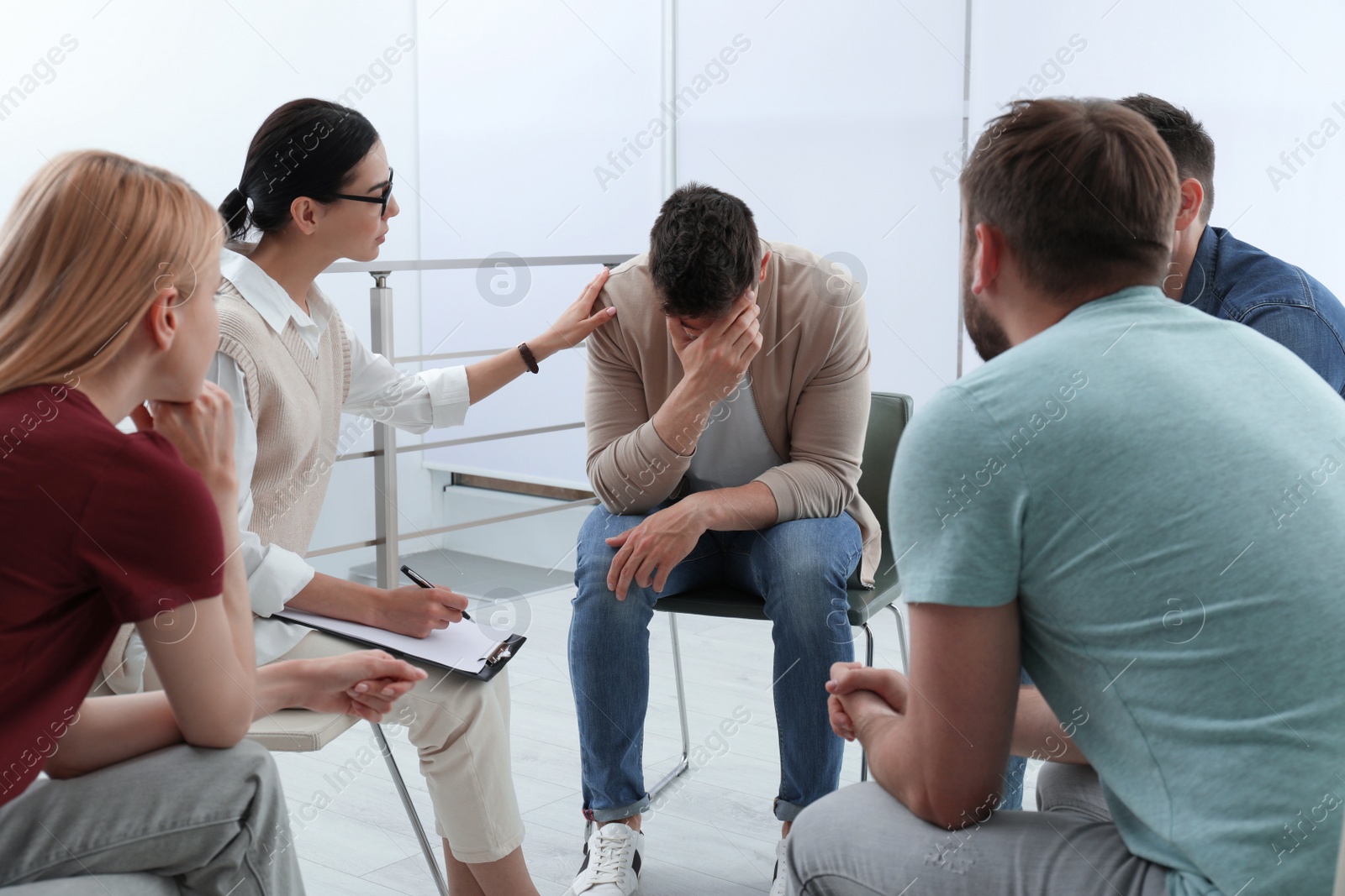 Photo of Psychotherapist working with group of drug addicted people at therapy session indoors