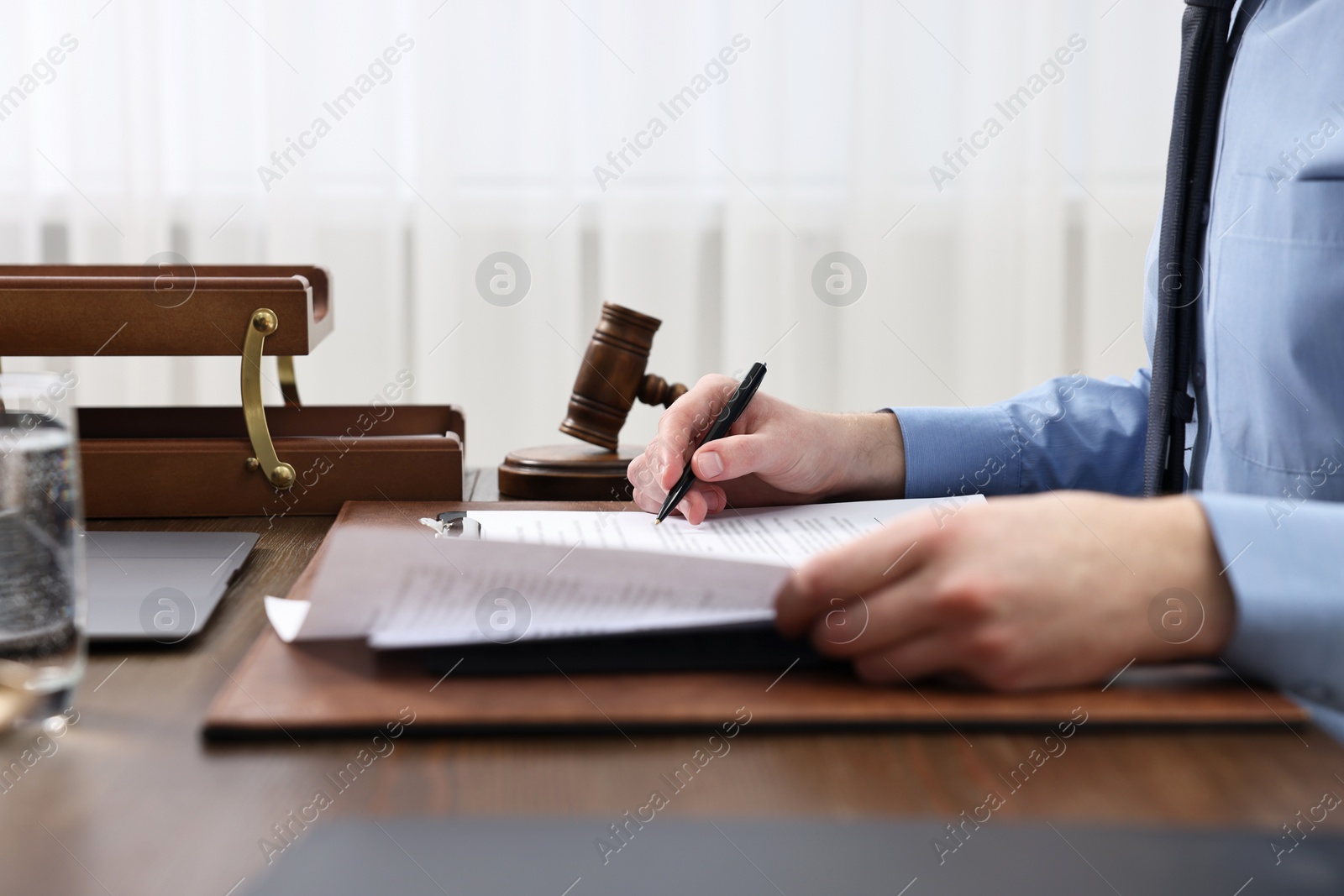 Photo of Lawyer working with documents at wooden table indoors, closeup