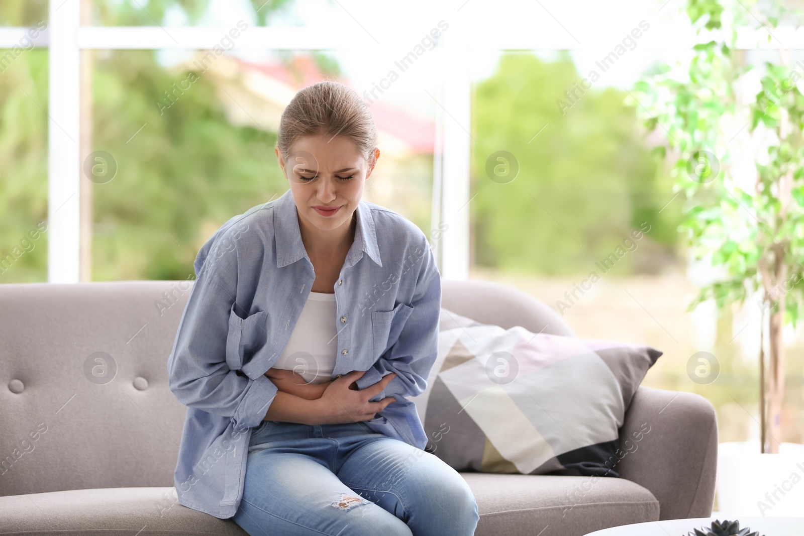 Photo of Young woman suffering from menstrual cramps at home. Gynecology