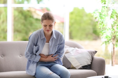 Young woman suffering from menstrual cramps at home. Gynecology