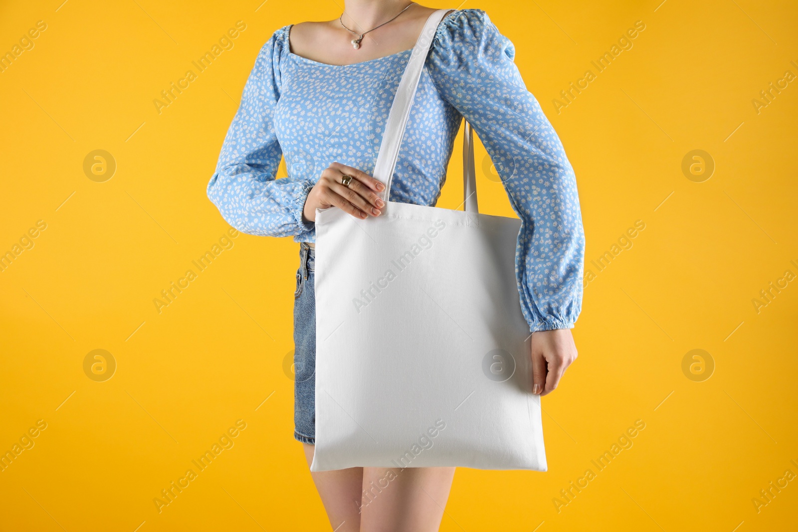 Photo of Woman with white textile bag on orange background, closeup. Space for design