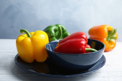 Dishware with ripe paprika peppers on wooden table