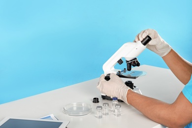 Photo of Male doctor using microscope at table, closeup with space for text. Medical object