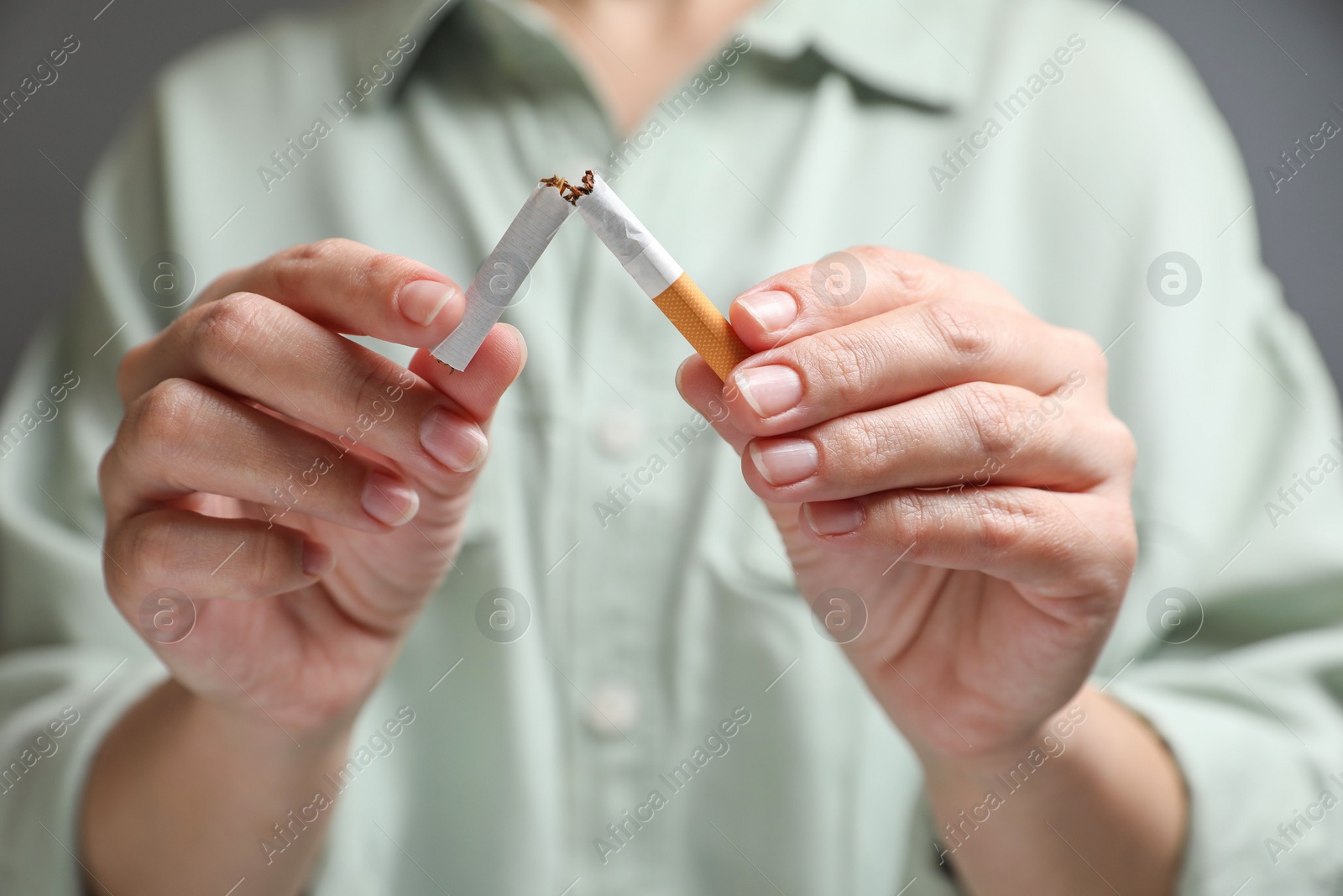 Photo of Stop smoking. Woman holding broken cigarette on grey background, closeup