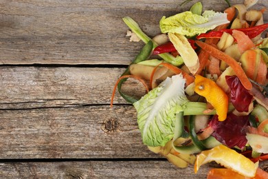 Photo of Peels of fresh vegetables on wooden table, top view. Space for text