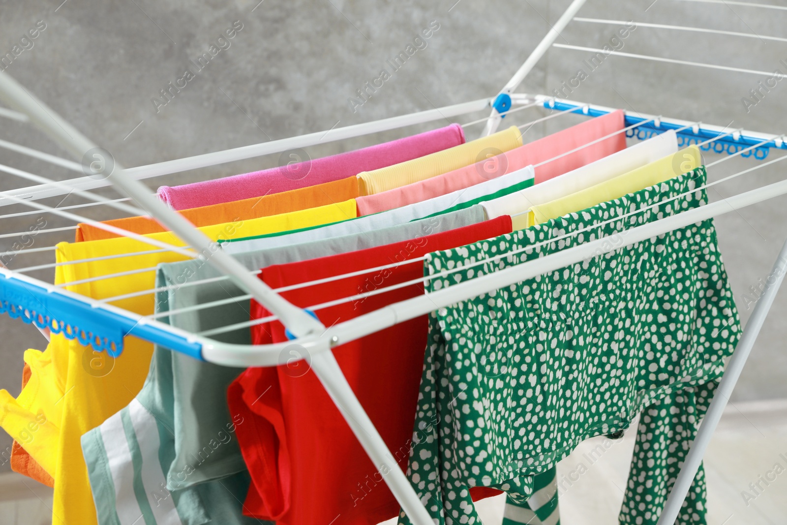 Photo of Different apparel drying on clothes airer indoors