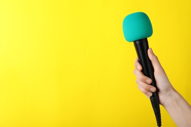 Woman holding microphone on color background, space for text