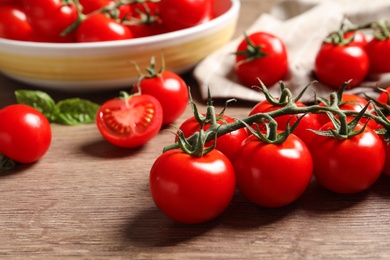 Photo of Branch of cherry tomatoes on wooden background