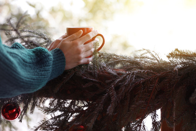 Woman with drink near decorated railing, closeup. Winter vacation