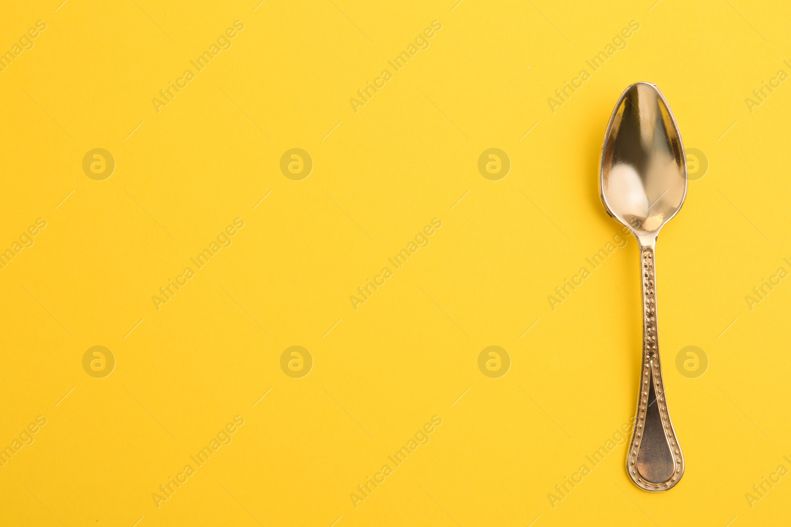 Photo of Clean tea spoon and space for text on color background, top view