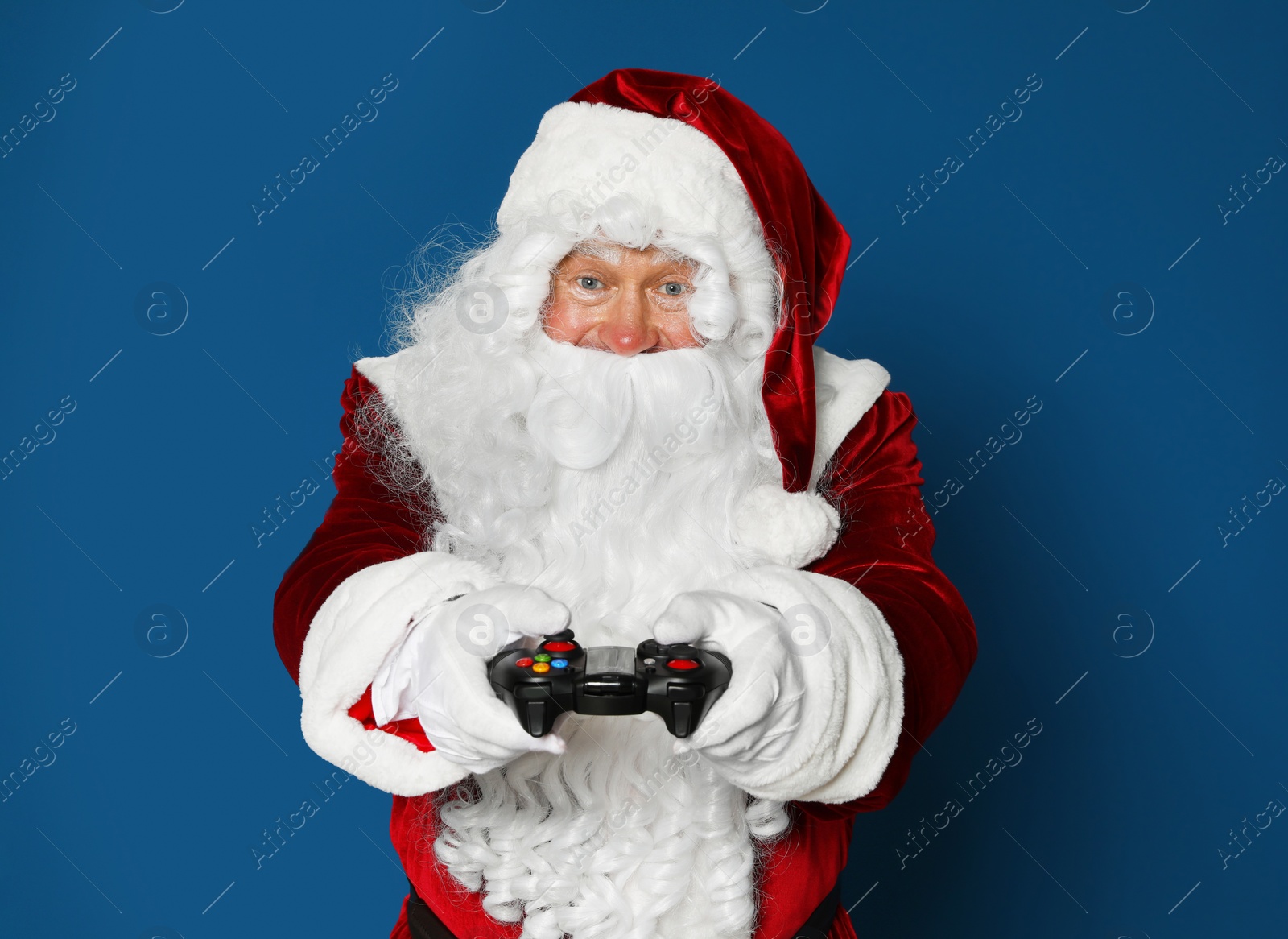 Photo of Authentic Santa Claus with game controller on blue background